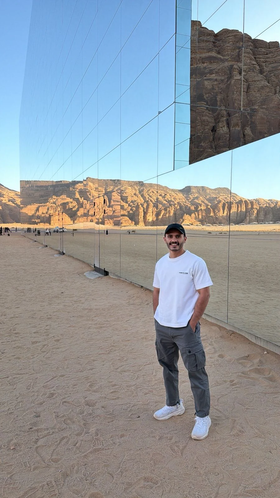 Anas Nassar beside a mirrored building in a desert landscape