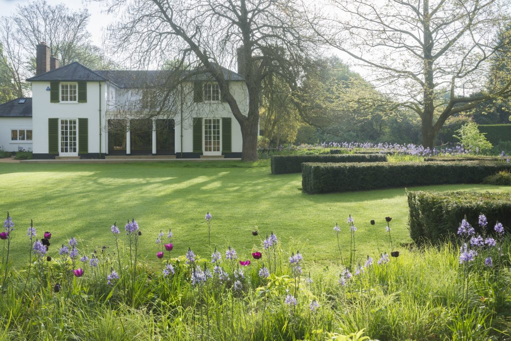Cory Lawn, next to Cory Lodge. A pristine green lawn, with flower beds of purple blooms, and immaculate hedges.