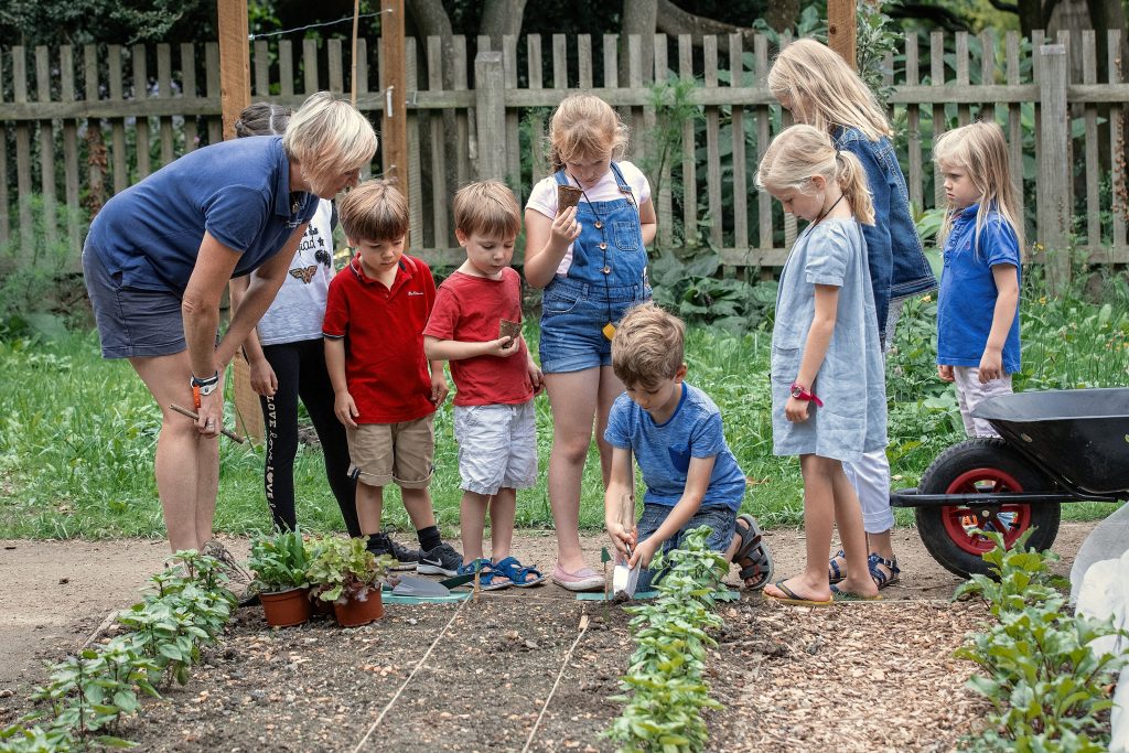 Eight children and a member of the horticulture team in the Schools' Garden.