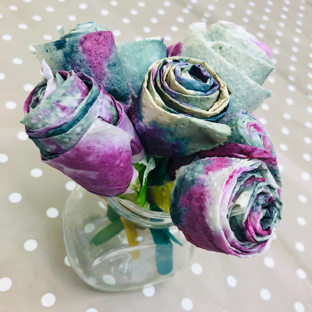 Bouquet of paper flowers coloured shades of purple, blue and green using pigments from blueberries.