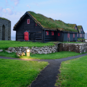 Old log farmhouse and Olavskirkjan Church in Kirkjubour village, Faroe Islands