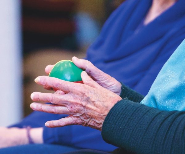 elderly person holding a small ball in their hands next to another person