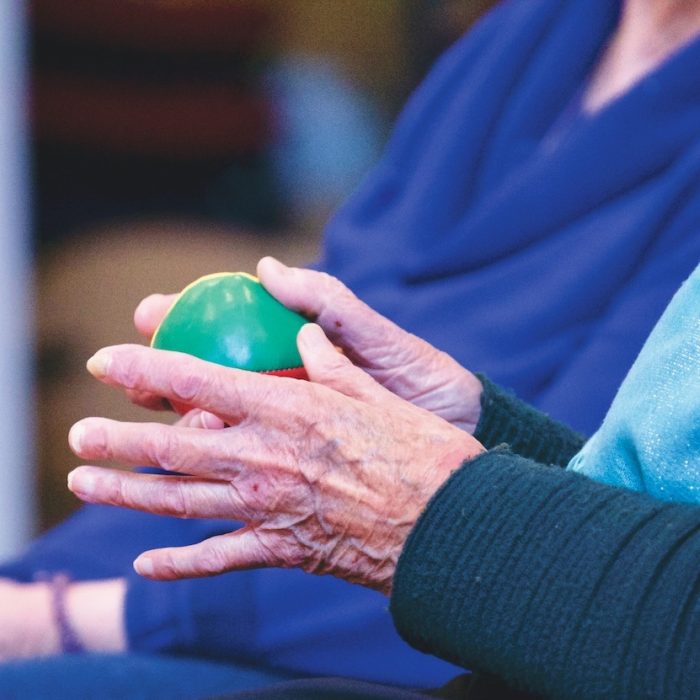 elderly person holding a small ball in their hands next to another person