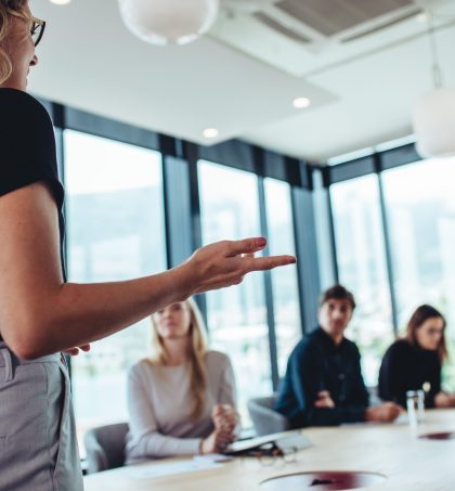 professional with Certificate in Leadership and Management Level 5 standing and leading business meeting
