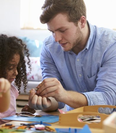early years educator enabling learning through play with a young child while using toys