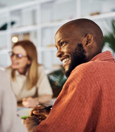 Man smiling during a conversation in a workplace meeting.