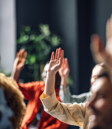 People raising their hands during a group discussion or training session.