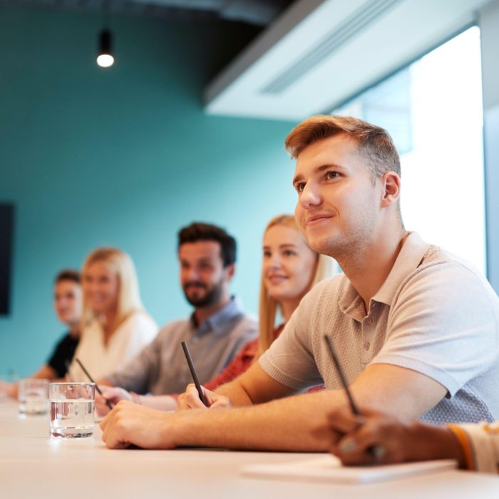 people looking up at person delivering meeting