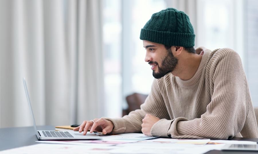 Mannlig studenter ser på pc og smiler