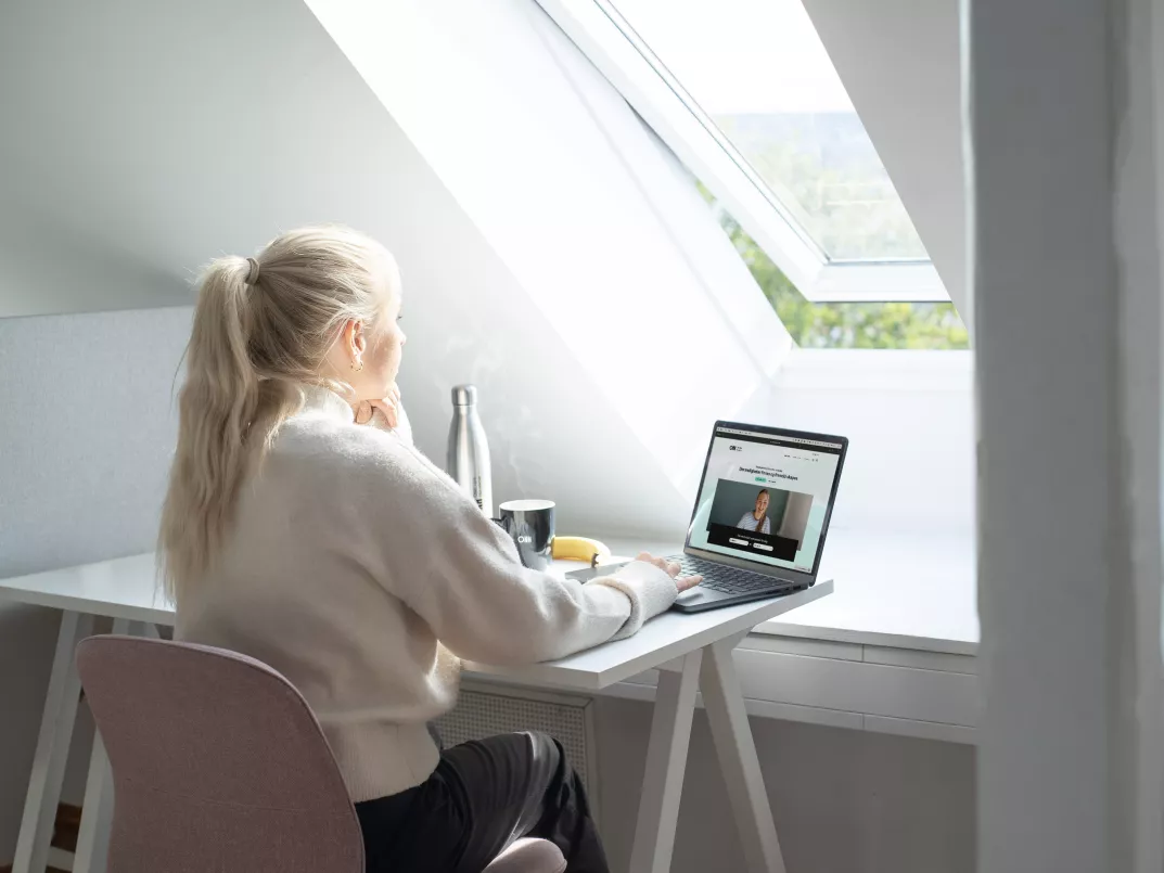kvinnelig nettstudent sitter foran pc ved vindu