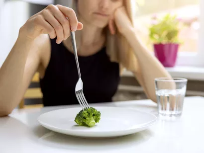 Ung jente sitter ved bord med gaffel i hånden