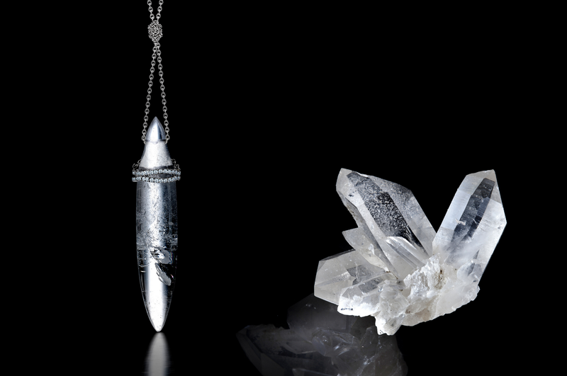 Bullet-shaped pendant in rock crystal showing icy white internal shards, & a rock crystal cluster, both on a black background