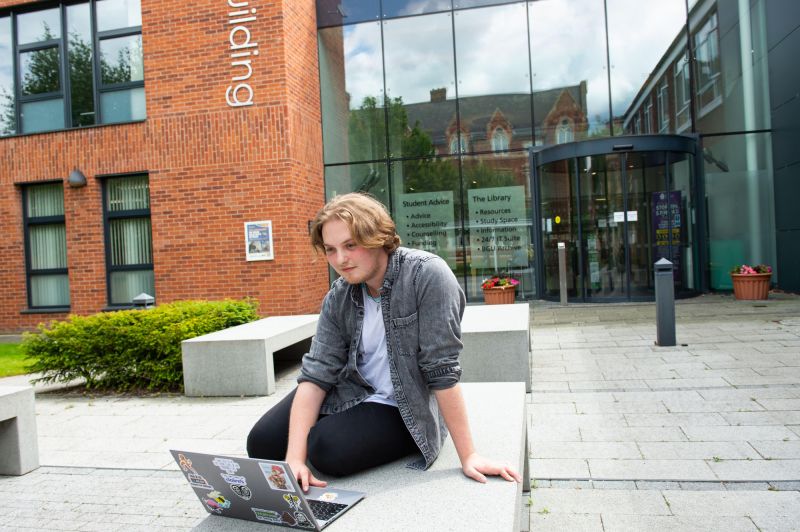 Student sits outside the library