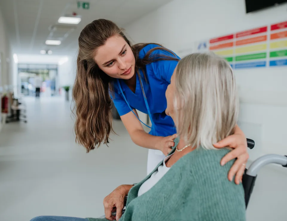 Young woman doctor taking care of senior woman at a wheelchair.