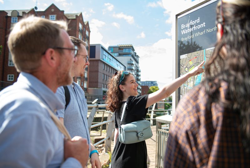 A student showing attendants to an open day around lincoln, pointing to a sign Brayford Waterfront