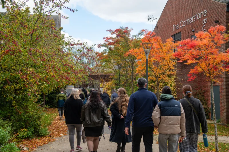 Photo taken during an Open Day: a group of people on a campus tour are shown walking across campus in the autumn.