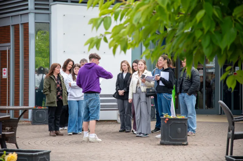 Photo taken during an Open Day: a campus tour group is standing outside the Robert Hardy building, with a student ambassador who is talking.