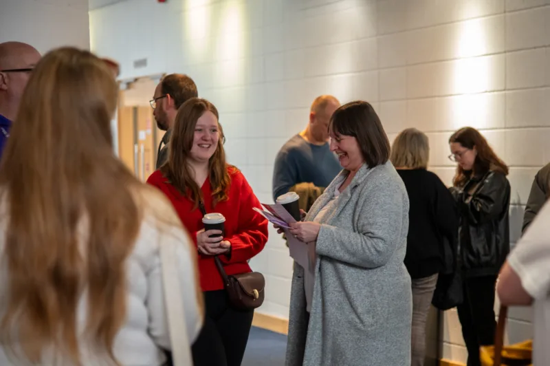 Photo taken during an Open Day: a prospective student is smiling, while her mum looks at the timetable.