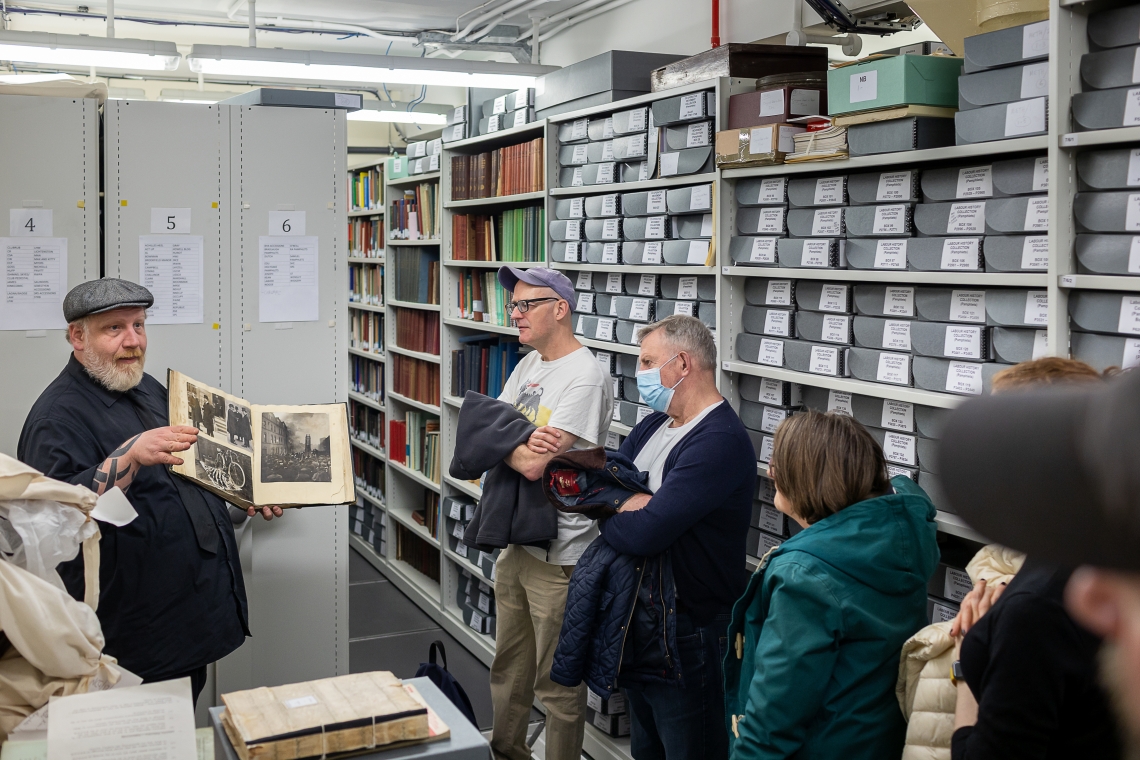 Image of Stefan Dickers holding a book open, while giving a tour of the archives.