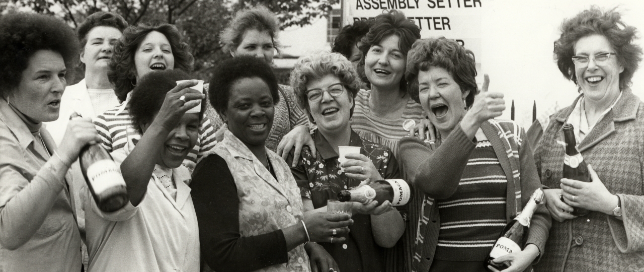 A black and white image of some happy women holding some bottles and cups.