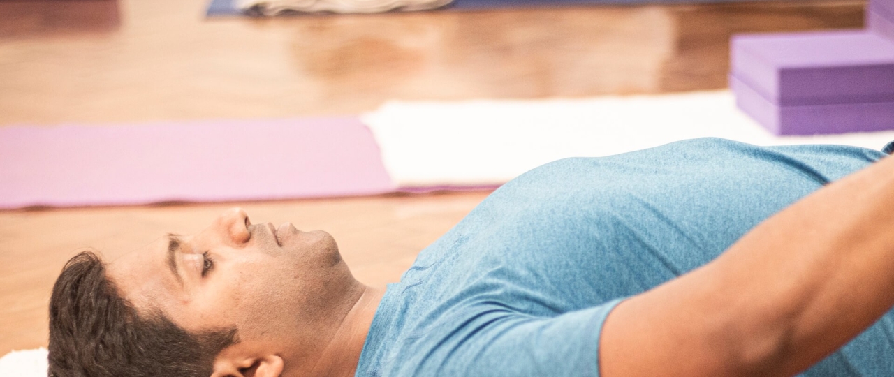 An Iyengar yoga workshop session at Bishopsgate Institute. A student is lying down on their map with their eyes closed.