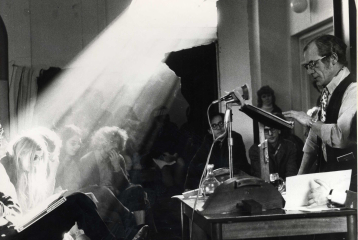A black and white photo of a man speaking in front of a room full of students. The image is from the History Workshop Audio Archive.