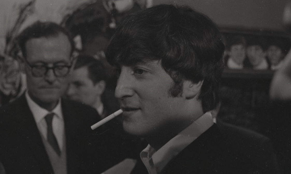A black and white photo of the Beatles being interviewed.