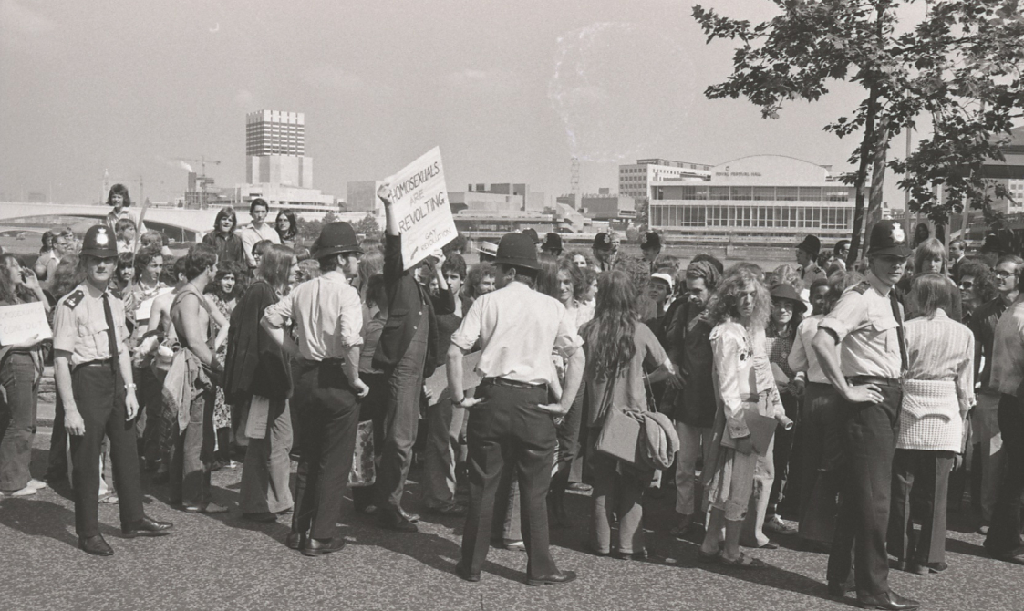 A picture from the second Pride march in 1973. A group of people are marching down from Embankment to Hyde Park. Police officers are standing by the protestors.