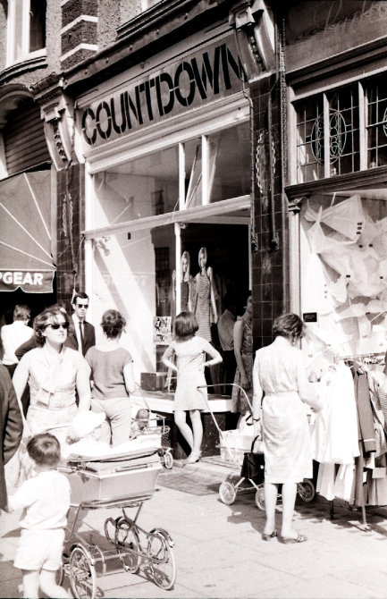 A black and white photo taken on a sunny day in June 1966 outside the Countdown shop on King's Road. People are milling past outside the shop front.