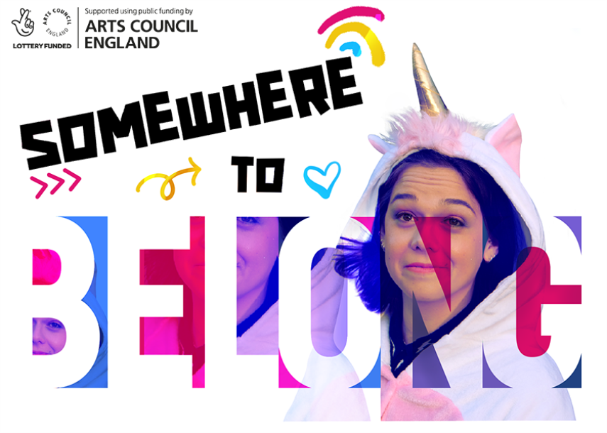A poster with the words "Somewhere to belong". There is also a young person wearing a unicorn onesie, with a hood.