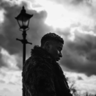 A black and white image of artist Wofai in silhouette to a dramatic sky.