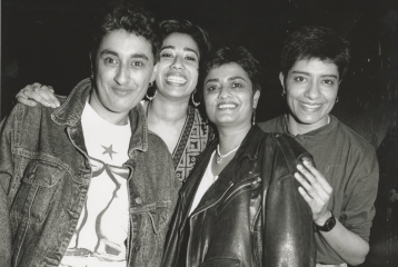 A black and white picture of four South Asian women looking at the camera and smiling