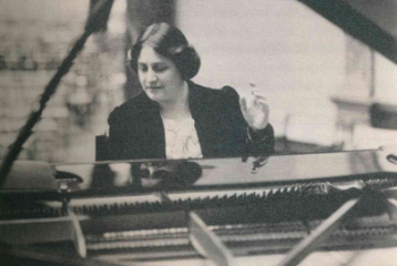 Black and white image of Myra Hess sat at her piano.