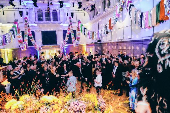 People dancing in a large hall which has been lit up for a disco and colourfully decorated.