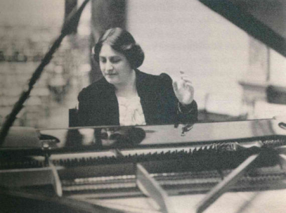 Black and white image of Myra Hess sat at her piano.
