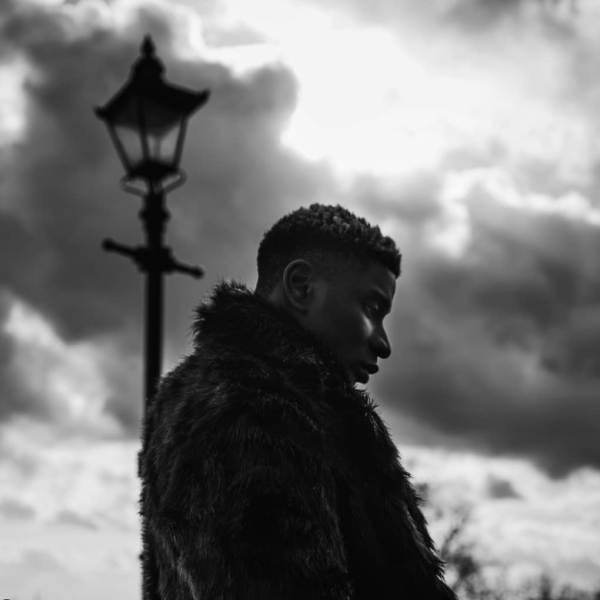 A black and white image of artist Wofai in silhouette to a dramatic sky.