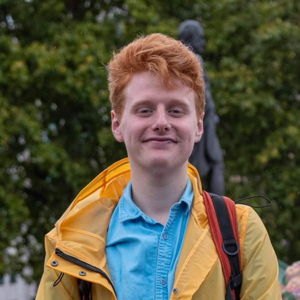 Portrait of Harry Holmes, who has short ginger hair and a yellow raincoat.