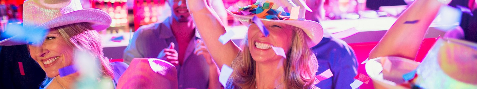 Five ladies wearing feathers and hats in a bar.