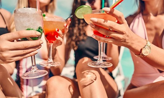 Three girls clinking cocktail glasses.