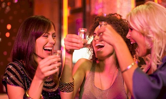 Three ladies taking shots in a bar.