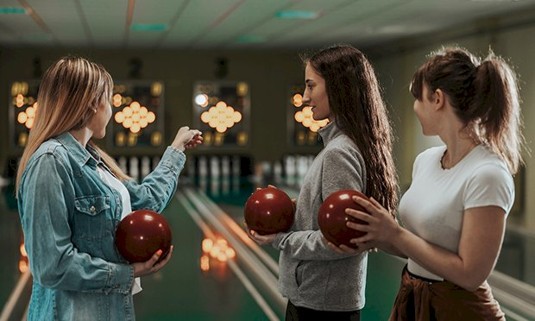 Three ladies taking part in bowling.