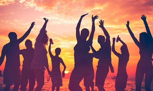 Ten people enjoying a party on the beach at sunset.