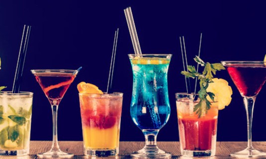 Three colourful cocktails on a wooden table. Discover the Lincoln Tipsy Tea hen party experience: