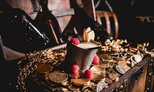 Cocktail in a chest of gold coins with fruit to garnish