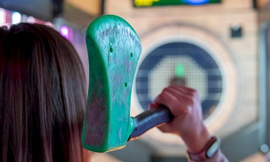 A ladie throwing an axe at a board.