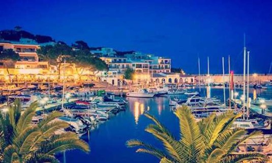 Sailboats and yachts mooring in the shimmering waters of the Puerto Portals marina at night. Discover Puerto Portals Hen Party ideas below: