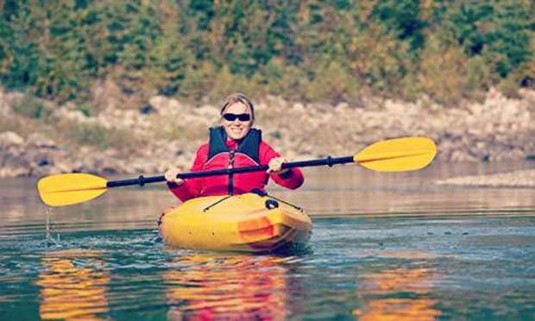 Hen in a red jacket and yellow canoe. Explore Vilnius Canoeing or Kayaking with your hen party: