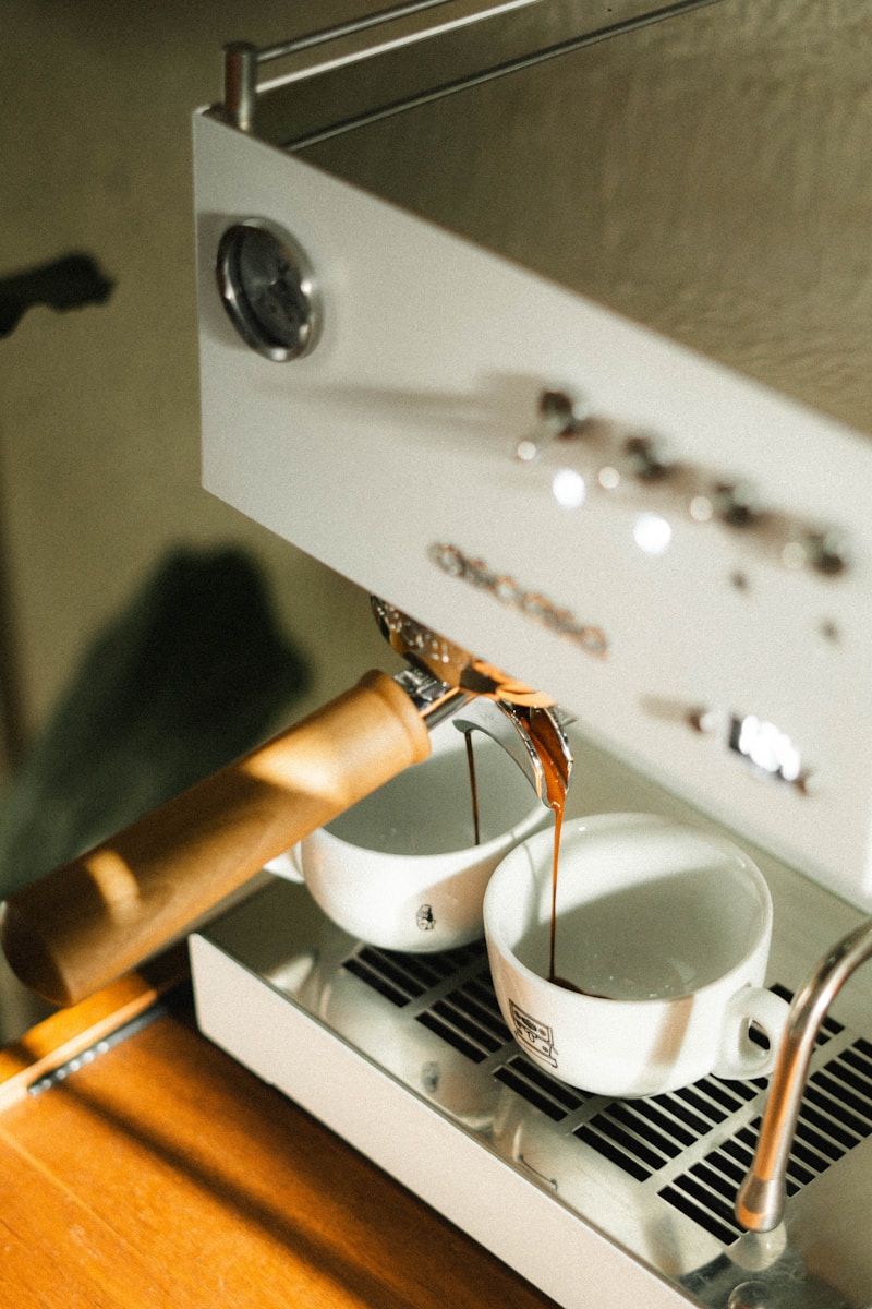 Coffee is brewing in two white cups.