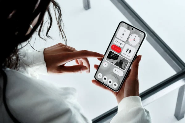 Person using the Nothing Phone (2) with a clean, widget-based interface displayed on the screen, showcasing the phone’s minimalist design and customized home layout