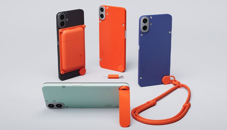 A collection of CMF Phone 1 models and accessories on a light grey surface. A black phone with an orange attachable wallet is in the background left. To its right are an orange phone and a blue phone, both with visible screws and circular accents. In the foreground, a mint green phone is lying on its side, and an orange lanyard attachment with a matching strap is in the bottom right.